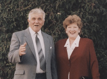 A man and woman pose outside