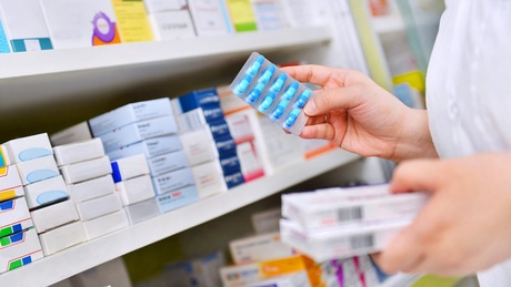 Image of pharmacist picking up a box of antibiotic medication