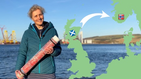 Dr Isla Graham stands holding a C-POD on the banks of the Cromarty Firth