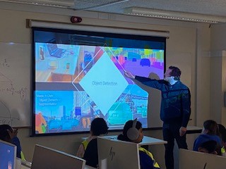 A man standing in front of a screen giving a presentation to a group of pupils
