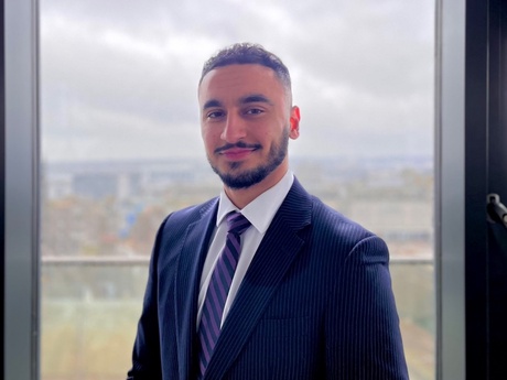 Head and shoulders shot of Hamza in a suit by a large window