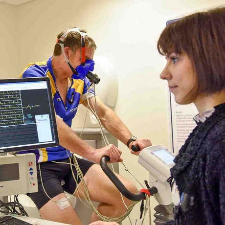 Man  on exercise bike is watched by researcher