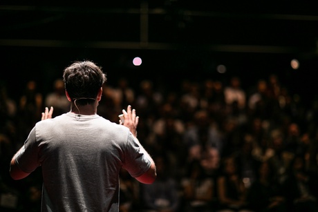 Man standing on stage presenting to a dark auditorium