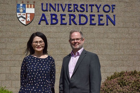 Dr Nan Liu and James Richardson standing outside the Business School in front of University branding