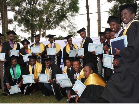 A group of smiling graduates in their gowns holding up their diplomas