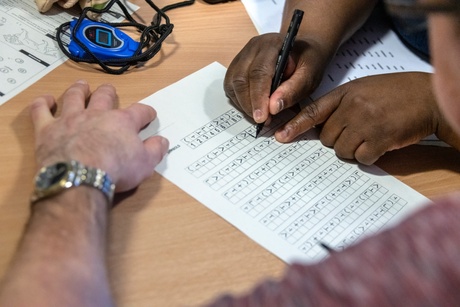 Close-up of a a paper cognitive test being completed by a patient with assistance from a clinician