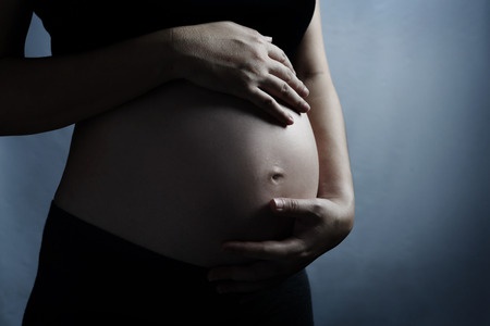 A visibly pregnant woman with her hand resting on her stomach