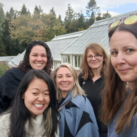 A photo of Carolina, Juliana, Katie, Jucilene and Sharon outside in a garden in front of a glass house