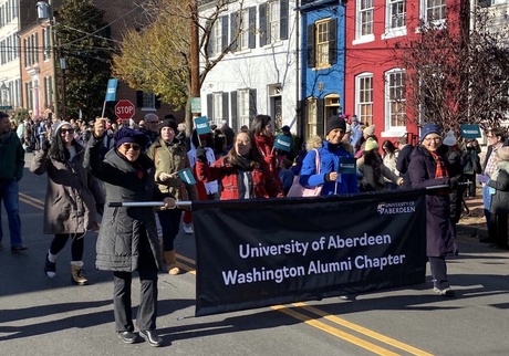 Alumni marching in a parade with a University banner