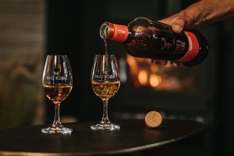Whisky being poured into two glasses with the Malt Room logo.