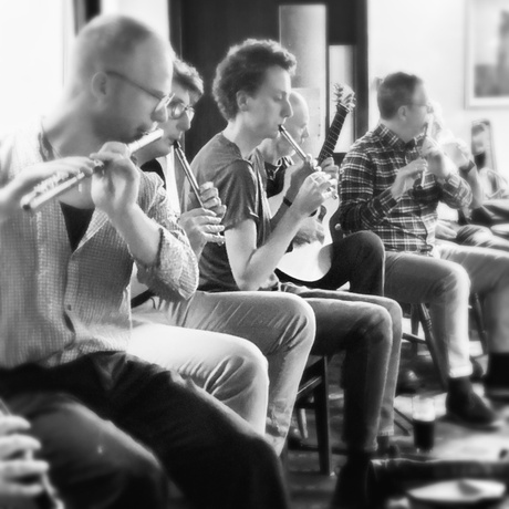 Musicians playing flutes, whistles and guitar indoors at an informal music session