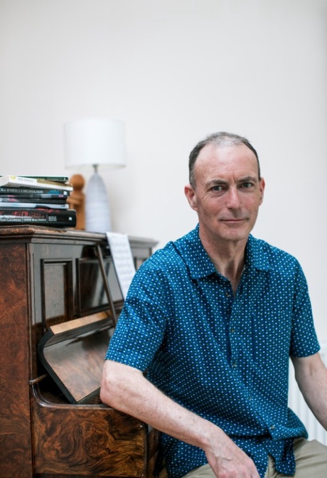 Man poses for camera sitting at piano