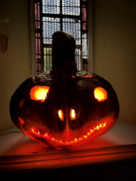 From darkness glows a long, eery smile eminating from a neep lantern
