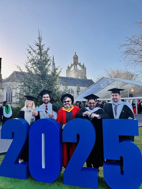 Graduates standing in front of a christmas tree on Aberdeen University campus