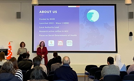 A photo of Bea Dawkins and Fionnuala Cousins presenting to an audience of health researchers at the University of Aberdeen