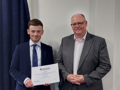 Image of Prize Winner Andrew Purdie, holding his certificate alongside Head of Law School Prof Greg Gordon