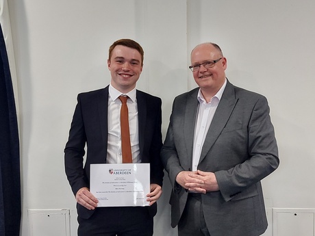 Photograph of Prize winner Ben Harvey, holding his certificate alongside Head of Law School Prof Greg Gordon