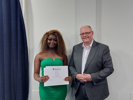 Photograph of Prize winner Faith Kargbo, holding their certificate, alongside Head of Law School Prof Greg Gordon