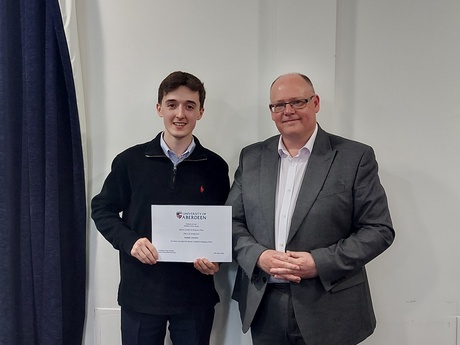 Photograph of Prize winner Joseph Lavallee, holding their certificate, alongside Head of Law School Prof Greg Gordon