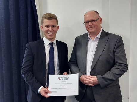 Photograph of Prize winner Murray Armitage, holding their certificate, alongside Head of Law School Prof Greg Gordon