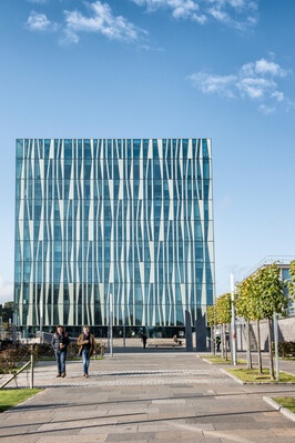external image of sir duncan rice library on a sunny day with two men walking away from the building