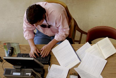 Image of student using laptop on desk, papers and notes next to laptop