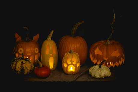 Different sized pumpkins with faces carved on them candles in them.