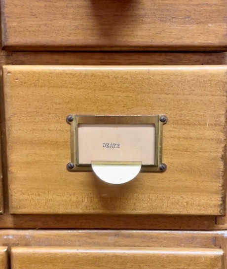 Wooden index drawer with a card with the word death on it. .