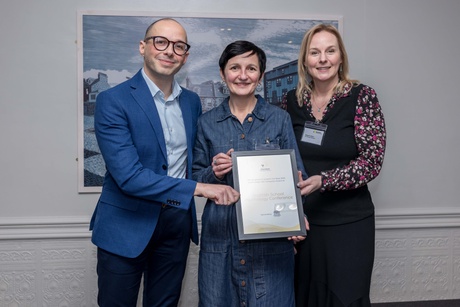 A man and two women standing together holding a certificate
