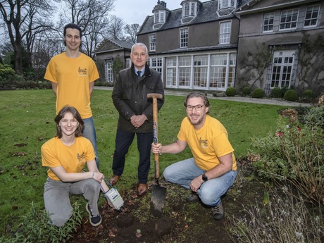 Four people standing in a garden with a shovel and a small piece of scientific equipment