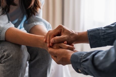 Two people holding hands, comforting each other