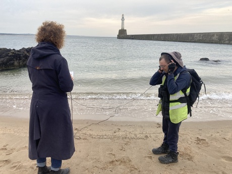 Two people on a beach with audio equipment