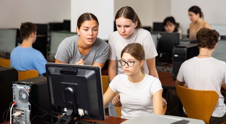 A teacher and two school pupils looking at a computer screen