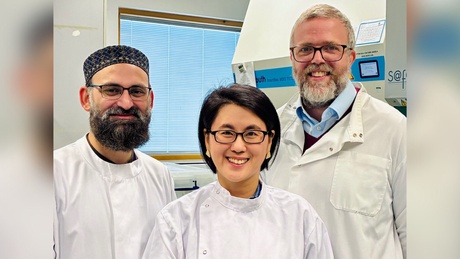 Three people in white lab coats in a laboratory