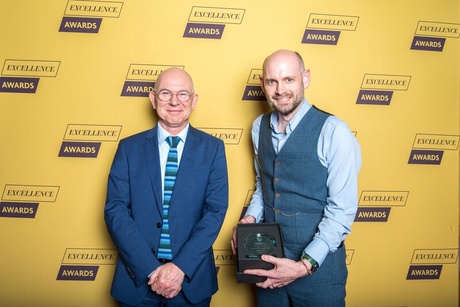 Professor George Boyne, Principal of the University of Aberdeen, stands next to Dr Malcolm Harvey, who holds an award in a display box
