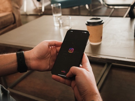 A person holding a smartphone with the Instagram app open