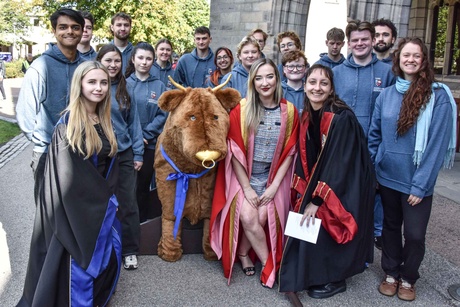 A group of people crowded around a bull mascot