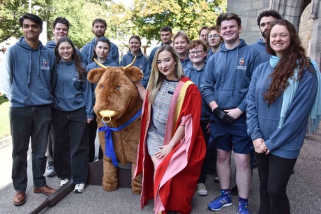 A group of people crowded around a bull mascot