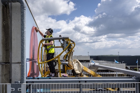 Artists installing a mural on a wall