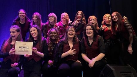 A group of women onstage celebrating with a certificate