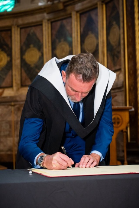 Someone signing a book in university robes