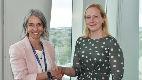 Two people shaking hands and smiling at the camera