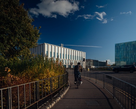 A person on a bike riding towards the Science Teaching Hub and the Sir Duncan Rice Library