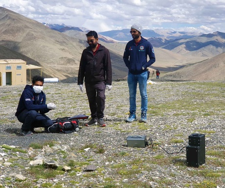 Three people with scientific equipment on a mountain range