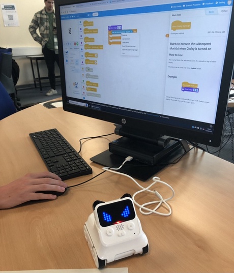 A small robot in front of a computer