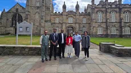 A group of people posing in front of King's College campus at the University of Aberdeen