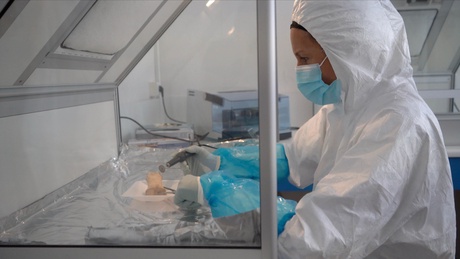 A scientist analysing a bone sample in a sterile lab
