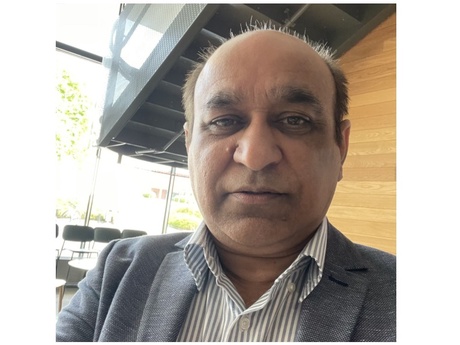 Head and shoulders image of a man in a striped shirt and grey jacket