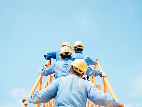 Oil workers climbing a ladder, viewed from behind