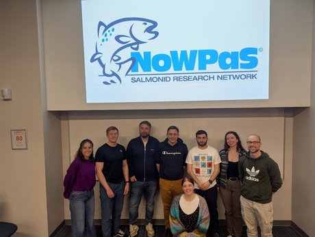 Lauren and others who attended the NoWPaS workshop stood under a screen displaying the NoWPaS logo